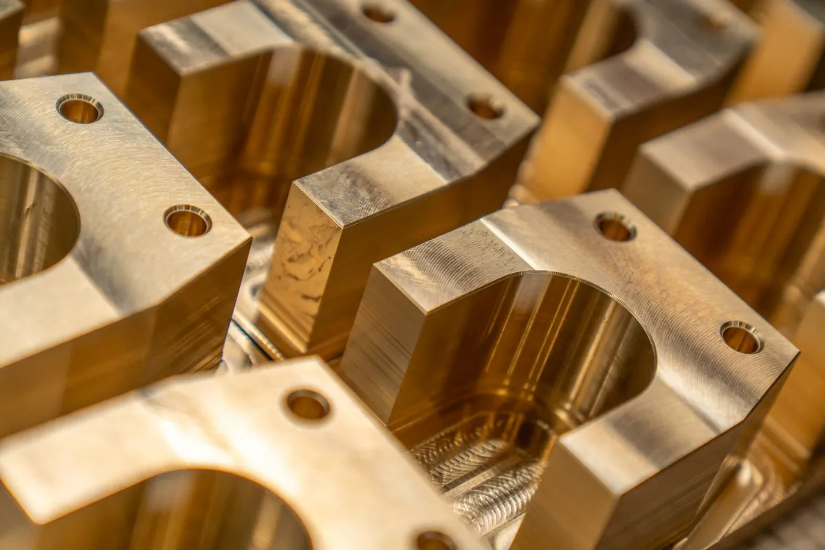 Stock photograph of machined metal blocks with milled recesses and drilled holes; not Omita products.